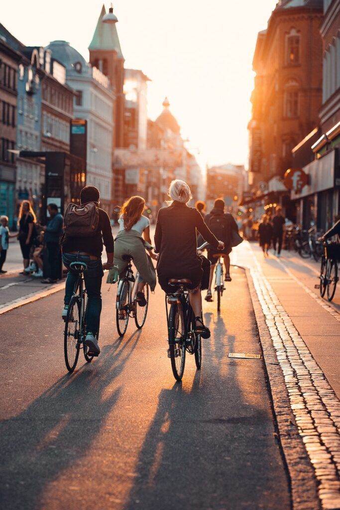 People Riding Bikes on City Street on Sunset