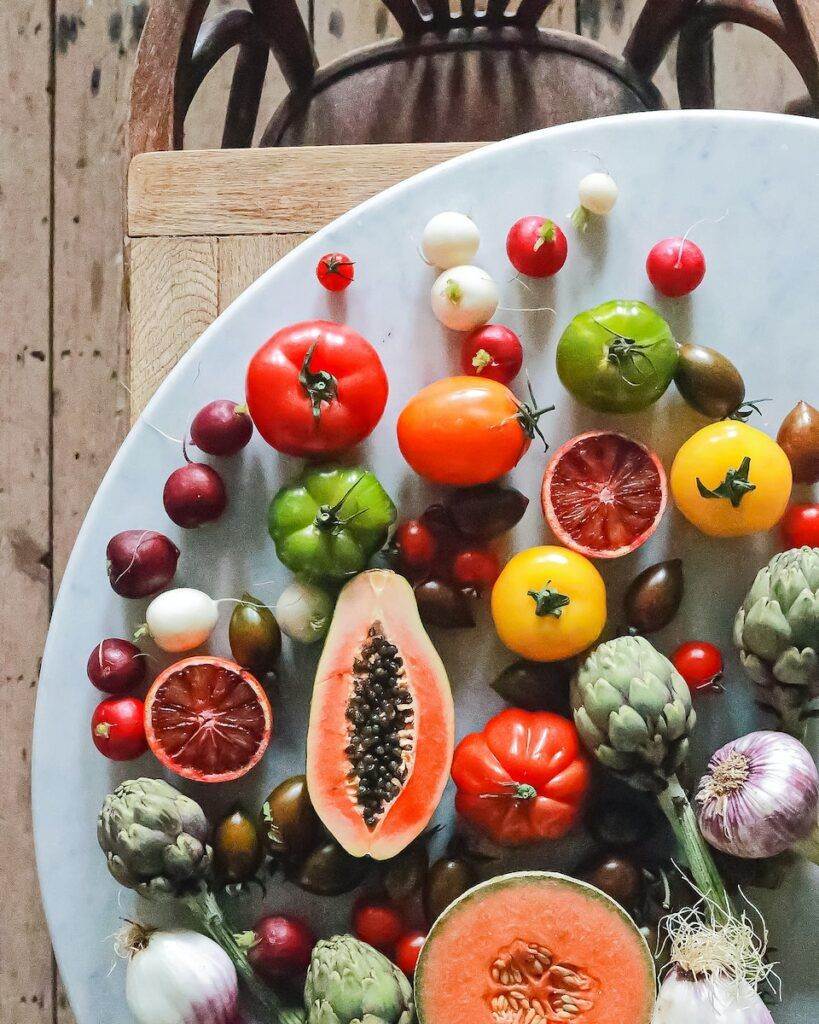 Top view of assorted exotic fruit with citrus and various vegetables of tomatoes and onions on round table